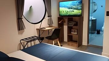 A hotel room with a bed, a desk, a chair, a television, and a wardrobe.