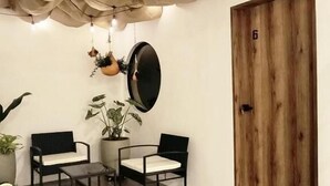 A room with a wooden door marked with the number 6, a round mirror, two chairs, a small table, and hanging lights. - Bluelux Med - B&B (Medellín)
