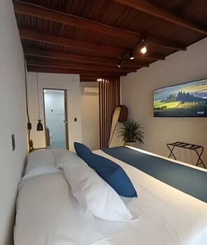 A bedroom with a bed, a TV on the wall, and a view of a landscape.