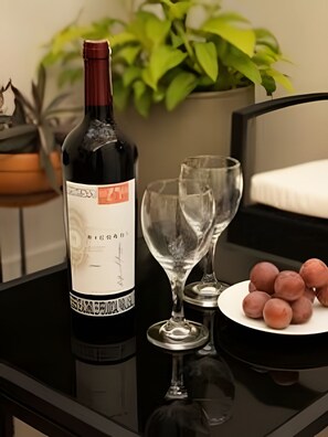 A bottle of wine, two glasses, and a plate with food on a reflective surface.