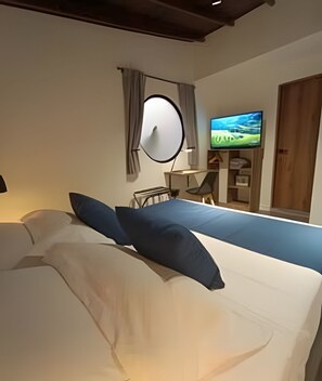 Habitación de hotel con cama, televisión y ventana con cortinas.