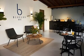 A modern hotel lobby with a reception desk, seating area, and a wall-mounted logo. - Bluelux MDE B&B (Medellín)