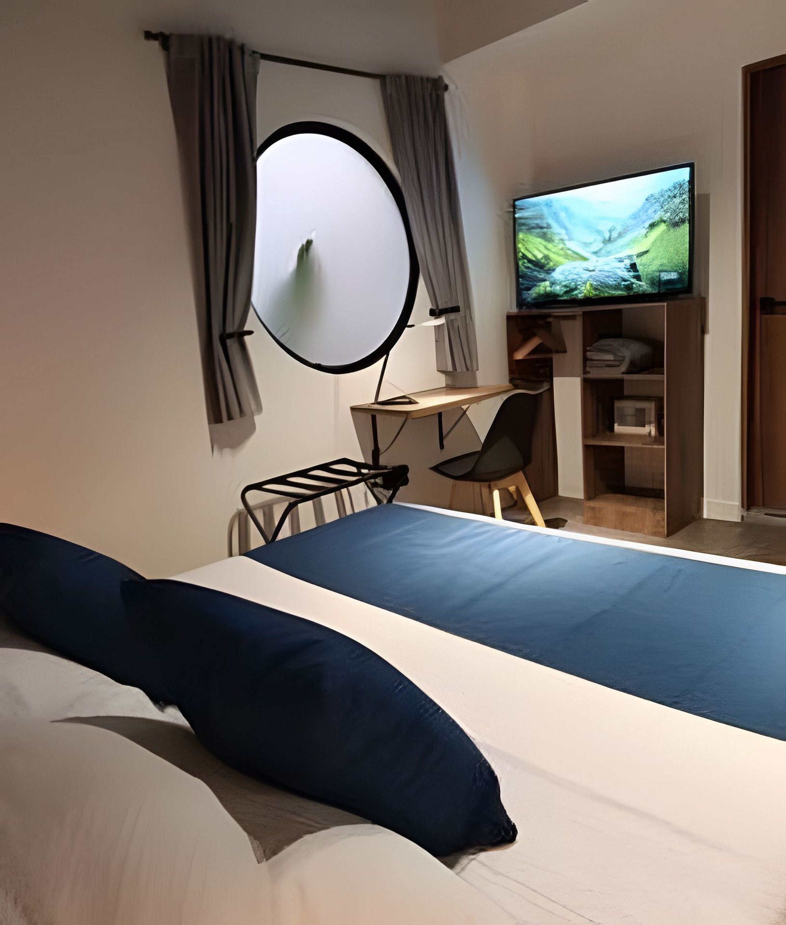 A bedroom with a bed, a desk, a chair, a television, and a wardrobe.
