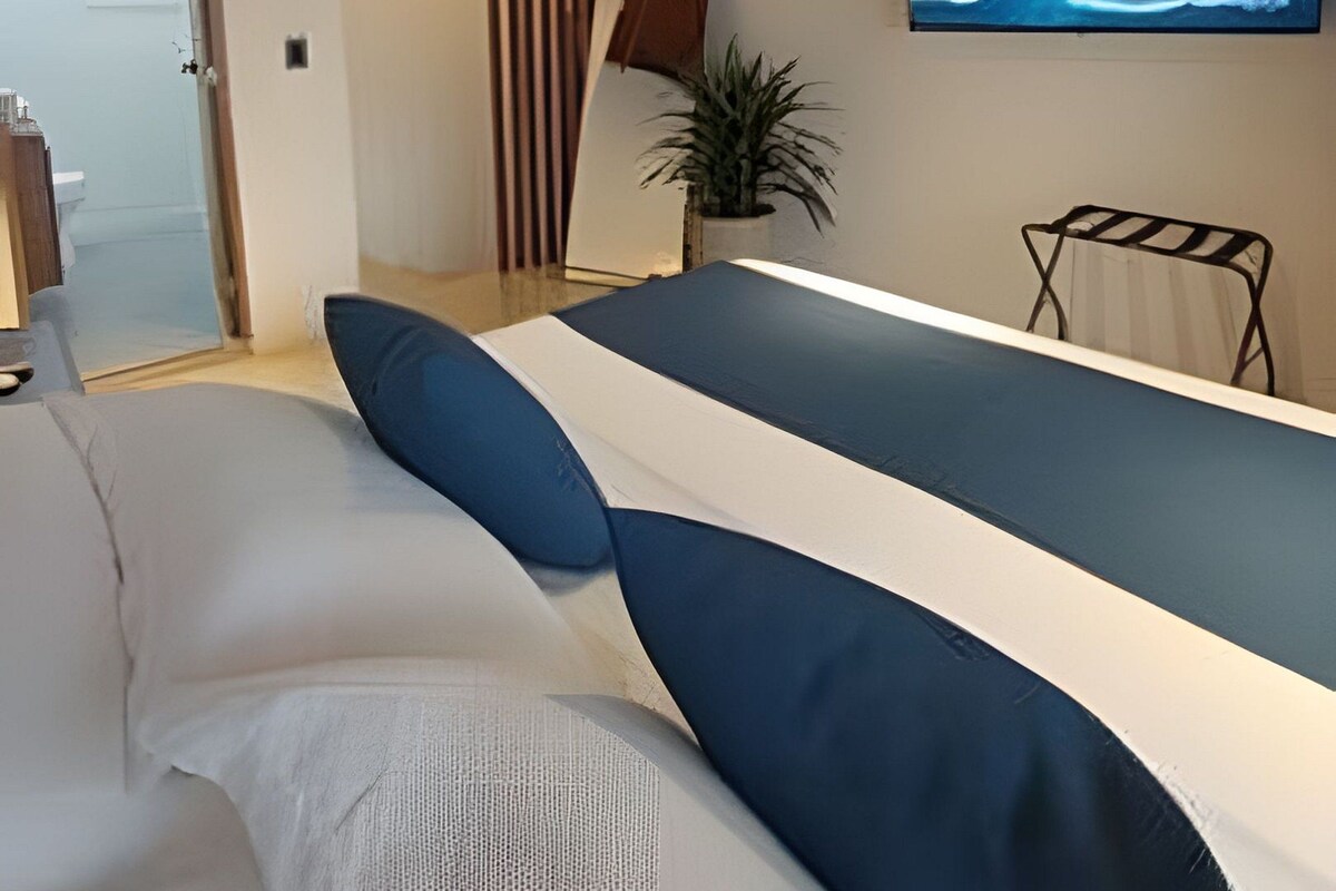 A modern bedroom with a bed, a TV mounted on the wall, and a staircase leading to another room.