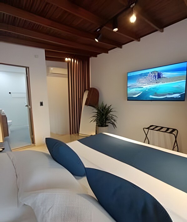 Un dormitorio moderno con cama, televisión montada en la pared y una escalera que lleva a otra habitación.