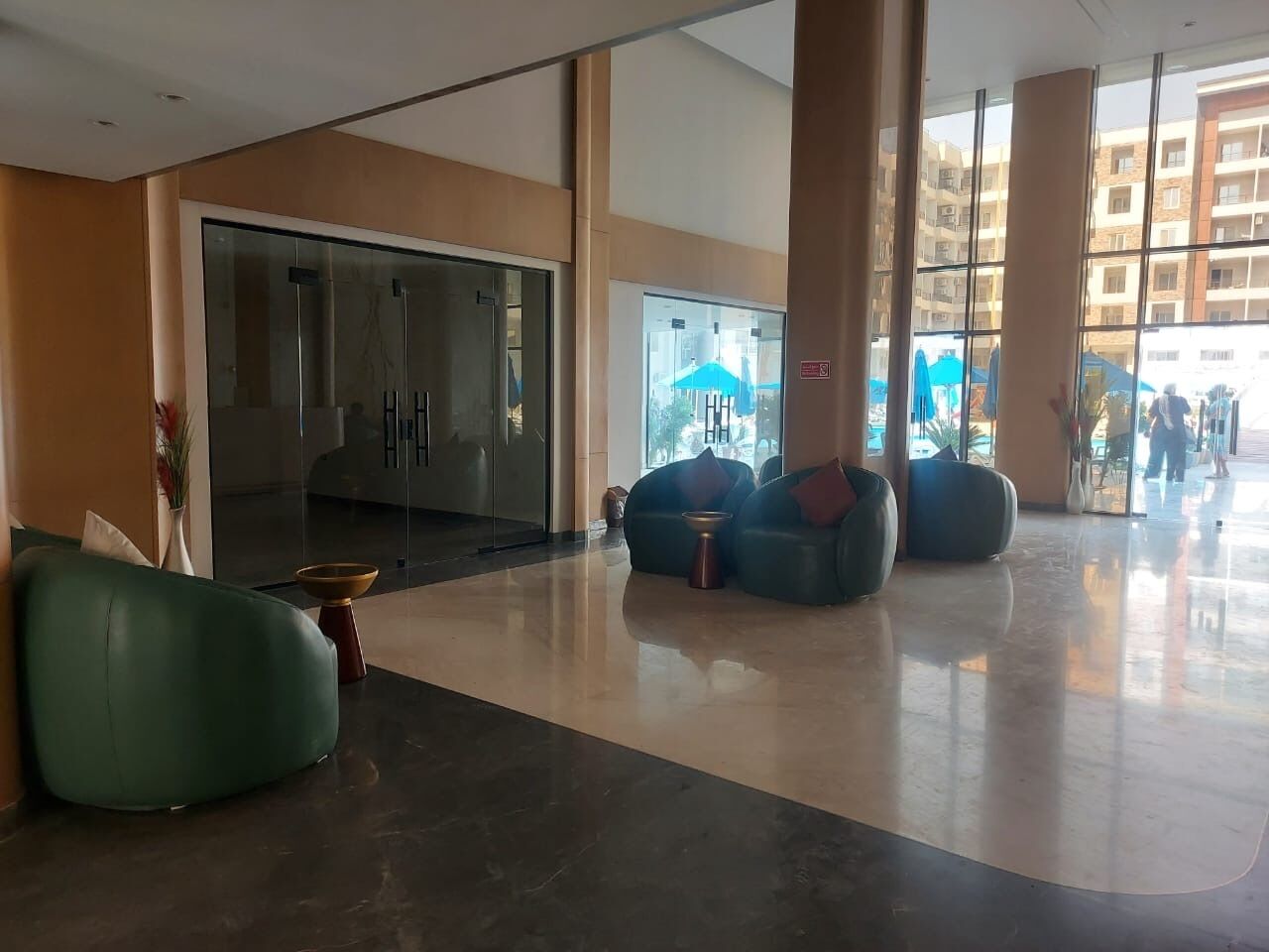 Un hall d’entrée spacieux avec une porte d’entrée en verre, des coins salon et de grandes fenêtres.