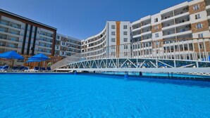 Een hotel met een zwembad, meerdere balkons en een brug die de gebouwen verbindt.