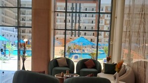 Een moderne hotellobby met grote ramen, uitzicht op een zwembad en comfortabele zitplaatsen.