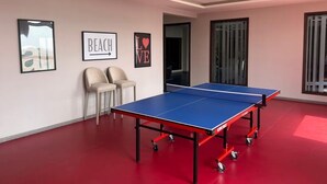 Et værelse med et ping pong bord, to stole og billeder i rammer på væggene.