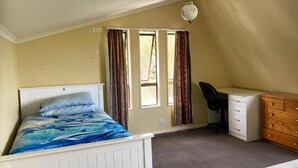 A bedroom with a bed, a desk, a chair, and a dresser. - Room-tranquil Browns Bay Guest Rooms wit (Auckland)