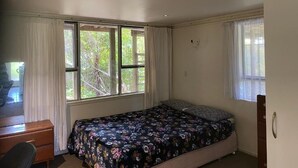 A bedroom with a bed, a desk, and a chair. - Room-tranquil Browns Bay Guest Rooms wit (Auckland)