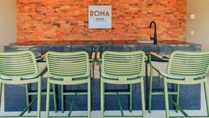 A kitchen with a brick backsplash, a sign reading 'ROMA 1888', and four green chairs. - Apt 2BR balcony, terrace, Heart of Guadalajara (Guadalajara)