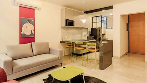 A modern living room with a sofa, a dining table, and chairs. There is a kitchen area with a microwave and a refrigerator. - Apt 2BR balcony, terrace, Heart of Guadalajara (Guadalajara)