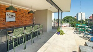 An outdoor seating area with green chairs and a sign reading 'ROMA 1888'. - Apt 2BR balcony, terrace, Heart of Guadalajara (Guadalajara)