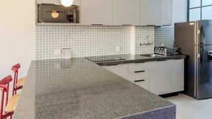 Eine moderne Küche mit einer Granit-Arbeitsplatte, Edelstahlgeräten und einer gefliesten Spritzschutzwand.