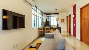 Ein modernes Wohnzimmer mit einer Couch, einem Fernseher und einem Essbereich mit Stühlen und einem Tisch.