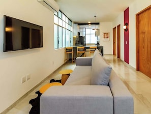 Una sala de estar moderna con un sofá, un televisor y un comedor con sillas y una mesa.