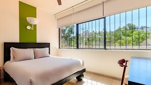 Ein Schlafzimmer mit Bett, einem Fenster mit Aussicht, einer Wandleuchte und einem Sessel.