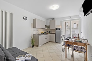 A modern kitchen with a dining area, a sofa, and a potted plant. - Casa Vergolano (Arco)