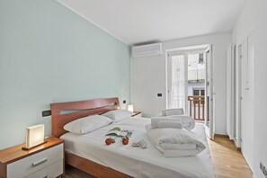A neatly made bed with white linens, a wooden headboard, and a bedside table with a lamp. - Casa Vergolano (Arco)