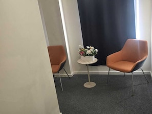 A room with two orange chairs, a small round table with a flower arrangement, and a dark curtain. - Charming B&B Retreat in the Heart of Gre (Manchester)