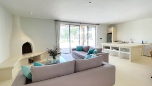 A modern living room with a sofa, a fireplace, and a kitchen area.