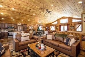 A log cabin interior with a kitchen, dining area, and living room furnished with leather sofas and a coffee table. - Journey's End - 4BR Chalet • 7 Min to Attitash (Bartlett)