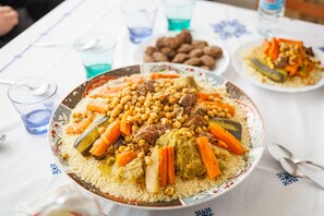 A table with a large plate of couscous, vegetables, and meat. - Berber Family (Tilmi)
