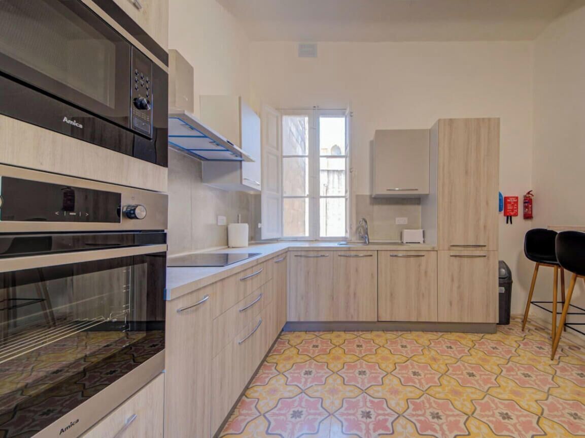 A modern kitchen with built-in ovens, a window, and a patterned floor.