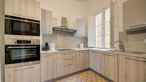 A modern kitchen with built-in appliances, a window, and a patterned floor.
