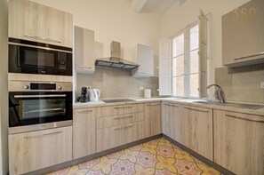 A modern kitchen with built-in appliances, a window, and a patterned floor.