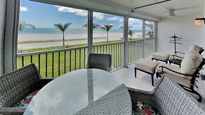 A balcony with a view of the beach, wicker furniture, and a ceiling fan. - Pointe South 105 | Gulf-Front + Newly Updated (Fort Myers Beach)