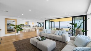 Un salon moderne avec un grand canapé, une table basse et une vue sur l’extérieur.