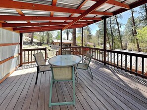 Eine Holzterrasse mit einem Glastisch und Stühlen, umgeben von einem Metallgeländer.