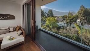 A modern room with a large sliding glass door leading to a balcony with a view of a mountain and trees. - Arcadia Yunjinyue Hotel (Dali)