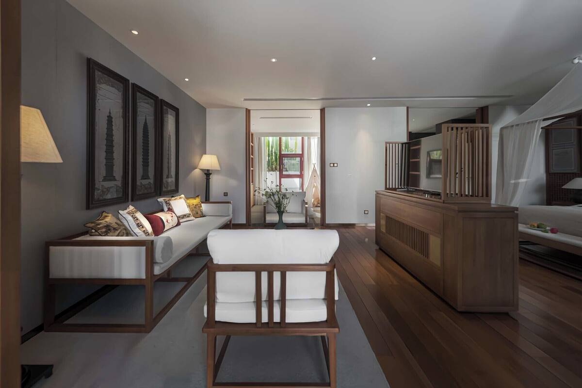 A modern living room with a sofa, a wooden chair, a TV, and a cabinet.