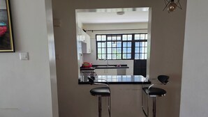 Una cucina con due sgabelli da bar, una finestra con infissi neri e un lampadario.