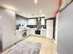 Una cocina moderna con electrodomésticos integrados, lavadora y un tapete gris.