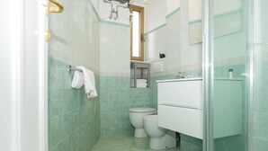 A bathroom with a toilet, a sink, and a shower area. - Casa Sai (Rome)