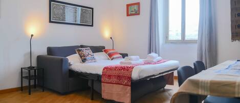 A bedroom with a bed, bedside tables, a window, and a table with chairs.