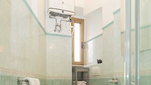 A bathroom with a toilet, a glass shower enclosure, and a white sink. - Casa Sai (Rome)