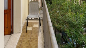 A balcony with a chair, an air conditioning unit, and a view of buildings. - Not Ordinary Apartment by Wonderful Italy (Noto)