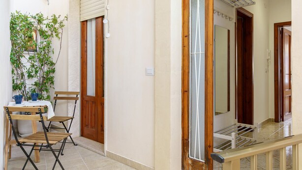 A room with a bamboo ceiling, a wooden door, a small table with chairs, and a potted plant. - Not Ordinary Apartment by Wonderful Italy (Noto)
