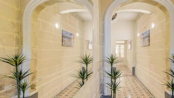 A hallway with arches, patterned floor tiles, and potted plants.