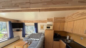 Eine gemütliche Küche mit Holzschränken, einer Mikrowelle und einem Essbereich mit Tisch und Bank.