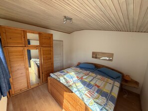 A bedroom with a wooden bed, a mirror, a ceiling fan, and a small bedside table. - Apartment 'Fewo 3 Garten' with Shared Garden and Wi-Fi (Gelting)