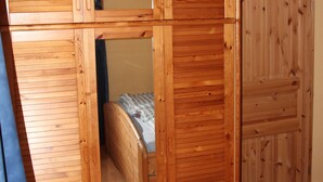 Ein Schlafzimmer mit einem Holzschrank, einem Bett und einem Spiegel.