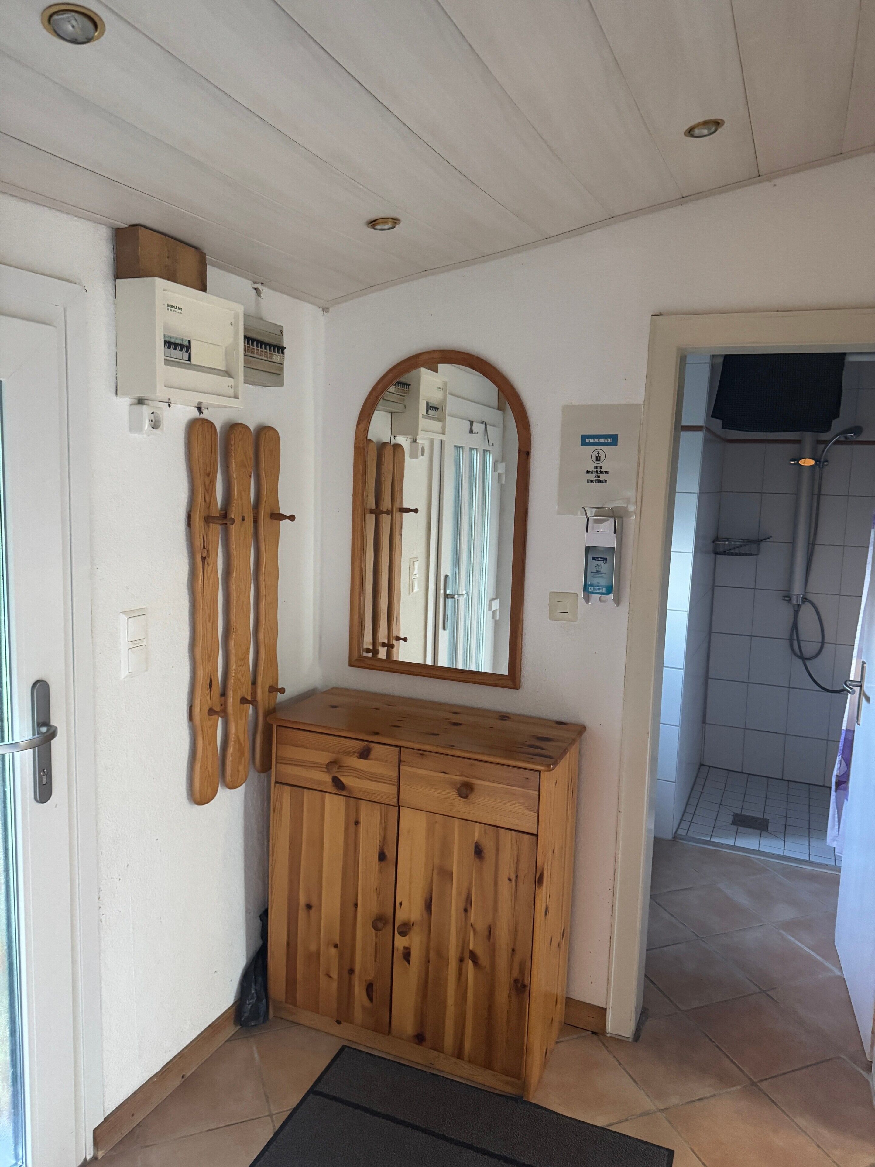 Une salle de bain avec un meuble-lavabo en bois, un miroir, une douche et un porte-serviettes.