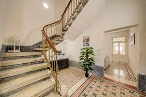 A staircase with ornate metal railings, a potted plant, and patterned floor tiles.
