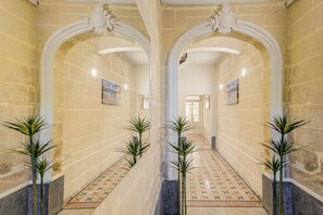 A hallway with mirrored arches, patterned floor tiles, and potted plants.